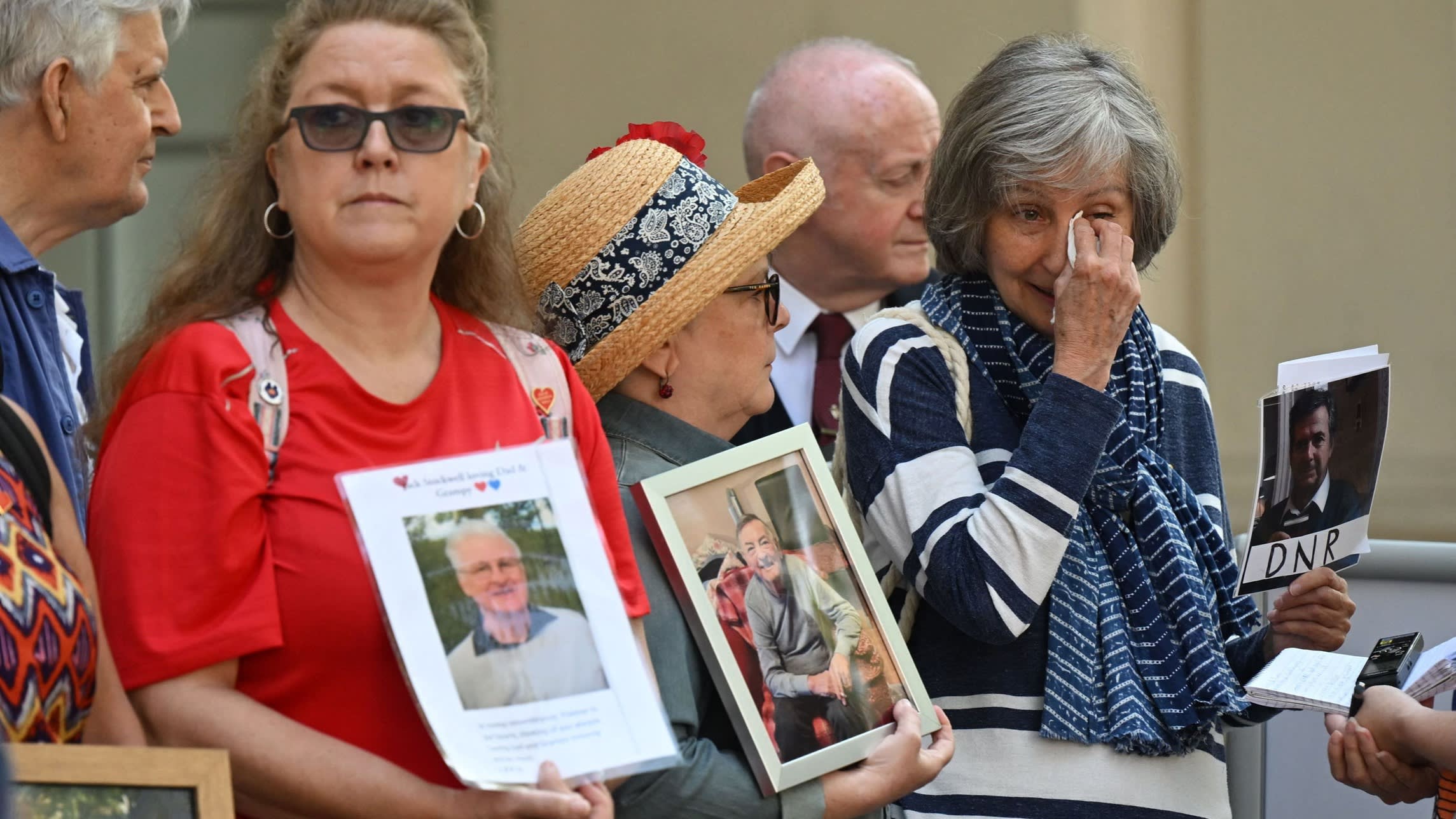 Members of the Covid-19 Bereaved Families for Justice hold photos of relatives who died during the pandemic